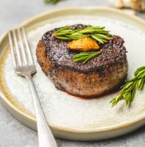 a piece of steak with rosemary on top