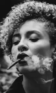 a woman with curly hair smoking a cigar