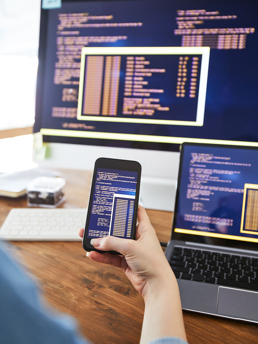photo of person checking website code on three different screen sizes