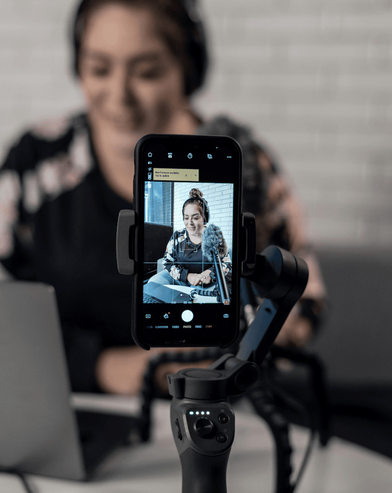 Phone screen showing women with headphones talking into microphone / Video marketing trends can be hard to keep up with, but are crucial to marketing success.