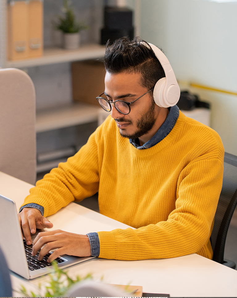 Person wearing headphones using laptop \ white paper